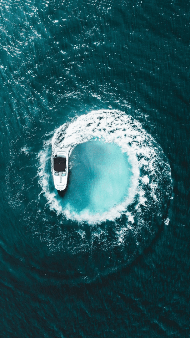 Boat making circular wake in ocean.